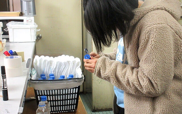 ペットボトルの蓋に穴を空けている天野さん